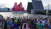 Orang-orang menonton kapal kuno dengan layar merah di Sungai Neva, St. Petersburg, Rusia, Jumat (24/6/2022) waktu setempat.  
