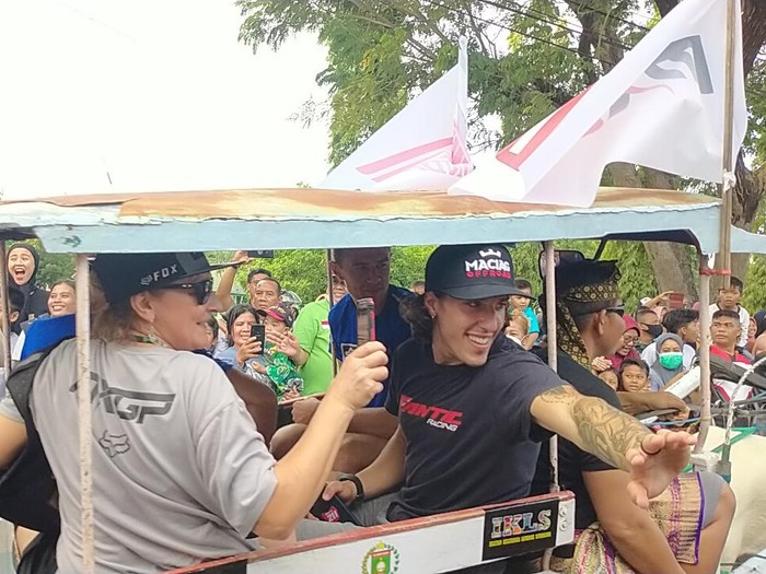 Warga terlihat berdesakan untuk dapat bersalaman dengan para pembalap. Mereka juga mengabadikan momen konvoi tersebut menggunakan handphone.
