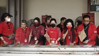 Puan yang mengenakan celemek merah terlihat ikut mengipas ikan yang sedang dibakar.