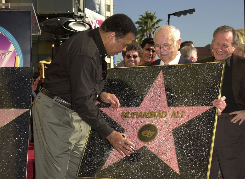 Muhammad Ali signing a replica of his Star on the Hollywood Walk of Fame (Photo by J. P. Aussenard/WireImage)