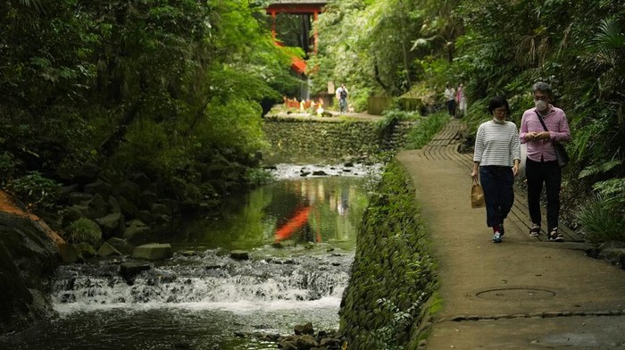 Japan Daily Life A woman prays at an alter placed near waterfalls, one of which is seen with a dragon god decoration, center right, near a Shinto shrine adjacent to the Todoroki Valley park in Tokyo, Tuesday, June 21, 2022. (AP Photo/Hiro Komae)