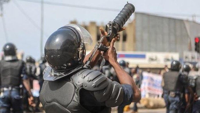 A Benin riot police officer holds a launcher as demonstrators gather to protest against the current presidents free-market reforms in Cotonou on March 9, 2018. - Police  fired teargas to break up an anti-government demonstration by Benins political opposition involving thousands of people, according to AFP reporters on the ground. Protesters had gathered in Cotonou, Benins economic hub, to march against President Patrice Talon but officers moved in when they strayed off an agreed course. Talon, a former businessman who made his fortune in cotton, was elected in April 2016, and has since tried to revamp the West African nations stuttering economy. But his proposals for free-market reform have sparked widespread concern, leading to a series of public sector strikes that have crippled the education, justice and health sector. (Photo by Yanick Folly / AFP)