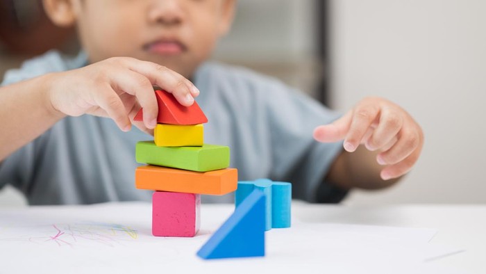 Close up Children hand Practice the skills of playing with wooden toys on the table in living room. Asian little boy education from home. Developing childrens learning before entering kindergarten