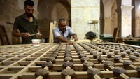 Para pekerja mengerjakan renovasi jendela kayu dari Masjid Umayyah di kota Aleppo, Suriah.