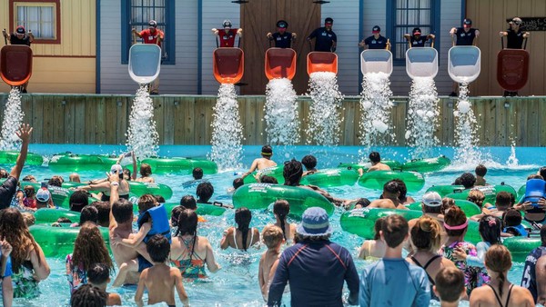 Sejumlah karyawan menuang es dari gerobak dorong ke kolam di Typhoon Texas Waterpark di Katy, Texas, AS, saat cuaca panas meningkat, Minggu, (26/6/2022).