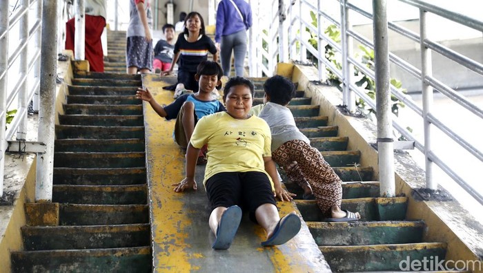 Minimnya lahan bermain membuat anak-anak menjadikan JPO sebagai tempat bermain perosotan. Meski begitu, mereka tetap ceria bermain di tempat penyeberangan tersebut.