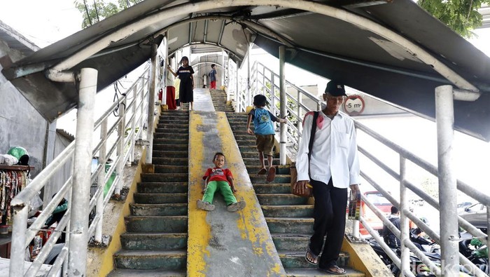 Senyum Ceria Anak-anak Main Perosotan di JPO Minimnya lahan bermain membuat anak-anak menjadikan JPO sebagai tempat bermain perosotan. Meski begitu, mereka tetap ceria bermain di tempat penyeberangan tersebut.