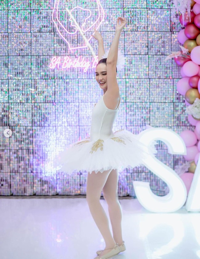 Shandy Aulia tampil mengenakan kostum ballerina berwarna putih dengan aksen keemasan. Seperti layaknya seorang ballerina, Shandy pun mengenakan stocking dan sepatu khusus ballet. Foto: Instagram/@shandyaulia