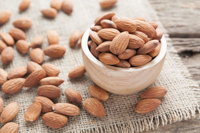 sekelompok almond dari mangkuk kayu dengan latar belakang kayu