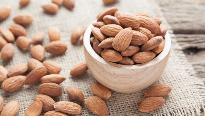 group of almonds  from wood bowl on wood background