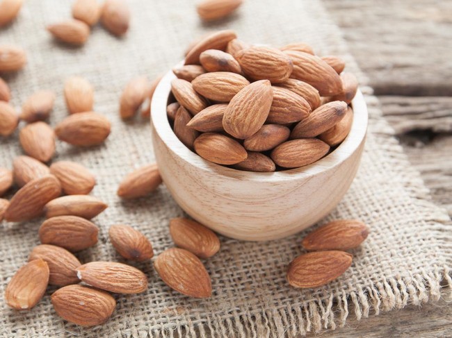 group of almonds  from wood bowl on wood background
