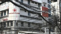 Terlihat salah satu tiang kabel semrawut yang berada tepat di depan gerai sepeda motor atau di samping gedung Palang Merah Indonesia (PMI) tak lagi berdiri kokoh. Tiang itu tampak miring dengan juntaian kabel-kabel semrawut yang menempel.