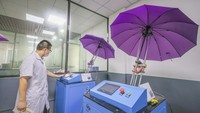 Seorang karyawan menguji coba payung yang telah selesai dibuat untuk memastikan kualitas payung. VCG via Getty Images