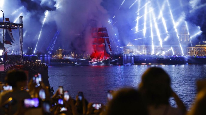 People watch fireworks and a brig with scarlet sails sailing on the Neva River during the Scarlet Sails festivities marking school graduation in St. Petersburg, Russia, early Saturday, June 25, 2022. (AP Photo/Dmitri Lovetsky)