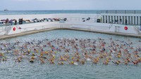 Para peserta mengenakan penutup kepala biru dan kuning, mereka berenang di kolam terbuka Jubile Pool, Penzance, dan membentuk gambar bendera Ukraina. Gambar ini akan terlihat dari atas. 