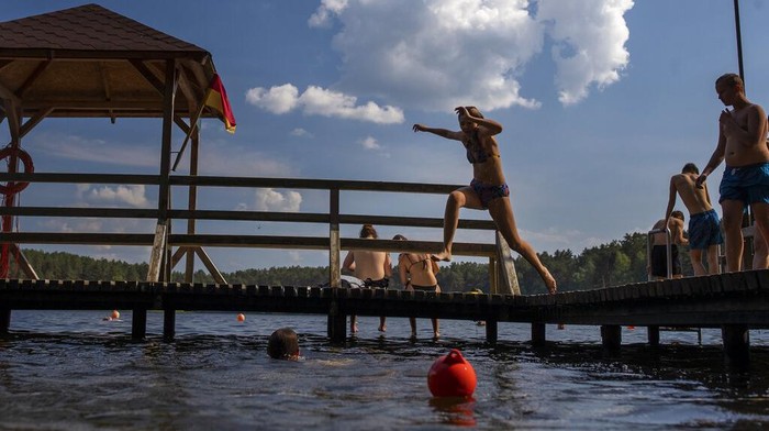 People enjoy the warm weather in the lake near Vilnius, Lithuania, Monday, June 27, 2022. The heat wave continues in Lithuania as temperatures rise to as high as 32 degrees Celsius (89.6 degrees Fahrenheit). (AP Photo/Mindaugas Kulbis)