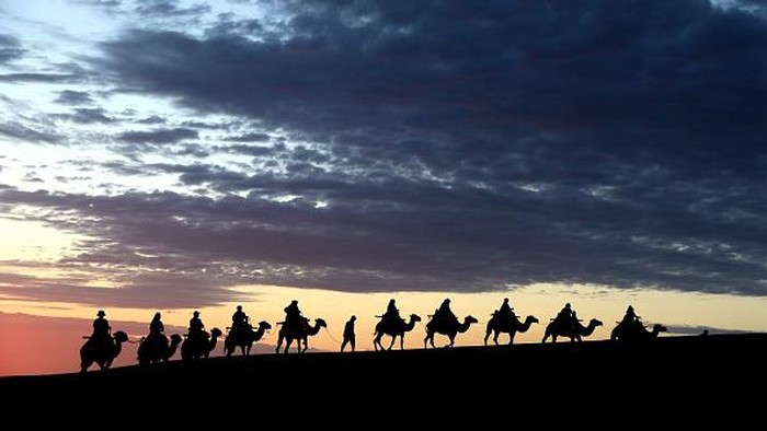 DUNHUANG, CHINA - JUNE 27: Tourists ride camels at the Mingsha Mountain and Crescent Spring scenic spot on June 27, 2022 in Dunhuang, Gansu Province of China. (Photo by Zhang Xiaoliang/VCG via Getty Images)