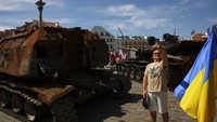 Seorang warga berfoto di antara tank-tank Rusia yang rusak yang dipamerkan di Polandia.