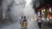 Wisatawan menikmati udara yang keluar dari air cooler di Taman Yuyuan, Shanghai, China, Selasa (28/8/2022) waktu setempat.
