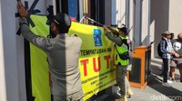 Petugas memasang banner berukuran besar di depan pintu masuk Holywings. Selain itu, pada bangunan itu tampak ada lagi tulisan Holywings. Foto: Jauh Hari Wawan S./detikJateng