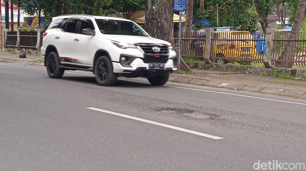 Mobil saat akan melewati lubang di Jalan Cik Ditiro Medan.
