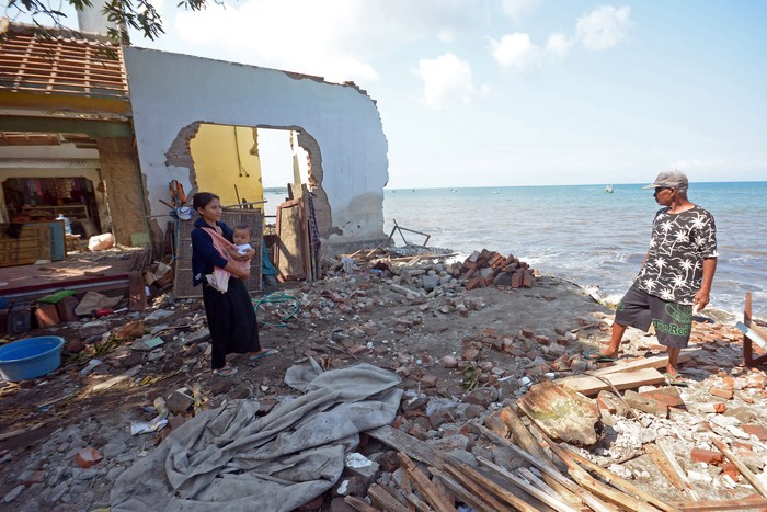 Warga melintas di dekat rumah yang rusak akibat terdampak abrasi di Pantai Pebuahan, Desa Banyubiru, Jembrana, Bali, Rabu (29/6/2022). Abrasi yang terjadi akibat gelombang tinggi di pantai tersebut menyebabkan lebih dari 10 rumah warga mengalami kerusakan dan nihil korban jiwa, hingga saat ini masih dalam penanganan BPBD Kabupaten Jembrana. ANTARA FOTO/Nyoman Hendra Wibowo/foc.