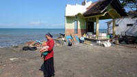 Warga melintas di dekat rumah yang rusak akibat terdampak abrasi di Pantai Pebuahan, Desa Banyubiru, Jembrana, Bali, Rabu (29/6/2022).   