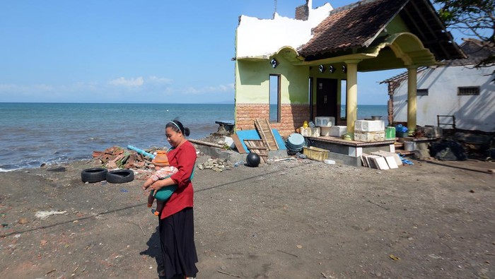 Nestapa Rumah di Pesisir Bali Tergerus Abrasi Warga melintas di dekat rumah yang rusak akibat terdampak abrasi di Pantai Pebuahan, Desa Banyubiru, Jembrana, Bali, Rabu (29/6/2022). Abrasi yang terjadi akibat gelombang tinggi di pantai tersebut menyebabkan lebih dari 10 rumah warga mengalami kerusakan dan nihil korban jiwa, hingga saat ini masih dalam penanganan BPBD Kabupaten Jembrana. ANTARA FOTO/Nyoman Hendra Wibowo/foc.