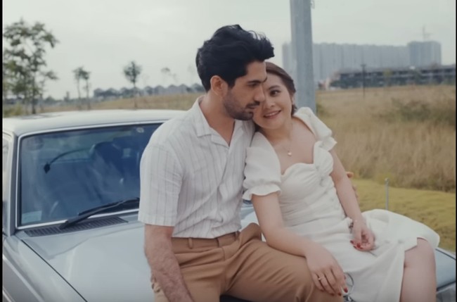 Gaya casual bisa diterapkan pada foto pre-wedding dengan konsep outdoor. Prilly tampil manis mengenakan gaun putih berpotongan leher square, sementara Reza Rahadian stylish dengan padanan kemeja stripe dan celana beige. Foto: Tangkapan Layar YouTube Prilly Latuconsina