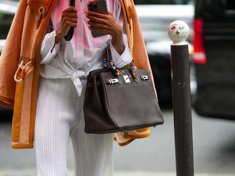Tas Hermes Birkin PARIS, FRANCE - JUNE 25: A guest wears a pink and white gradient pattern shirt, a brown and orange jacket, white ribbed flared pants, a dark brown shiny leather Birkin handbag from Hermes, a multicolored print pattern silk scarf from Hermes, outside the Hermes show, during Paris Fashion Week - Menswear Spring/Summer 2023, on June 25, 2022 in Paris, France. (Photo by Edward Berthelot/Getty Images)