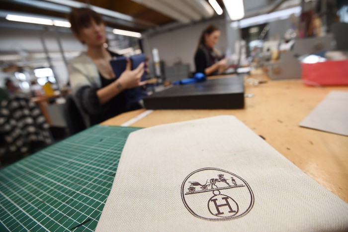 Workshop Tas Hermes This picture taken on January 6, 2022 shows an employee holding handbags at the leather goods workshop of French high fashion luxury goods manufacturer Hermes in Montbron some 28 kms East of Angouleme. (Photo by Philippe LOPEZ / AFP) (Photo by PHILIPPE LOPEZ/AFP via Getty Images)