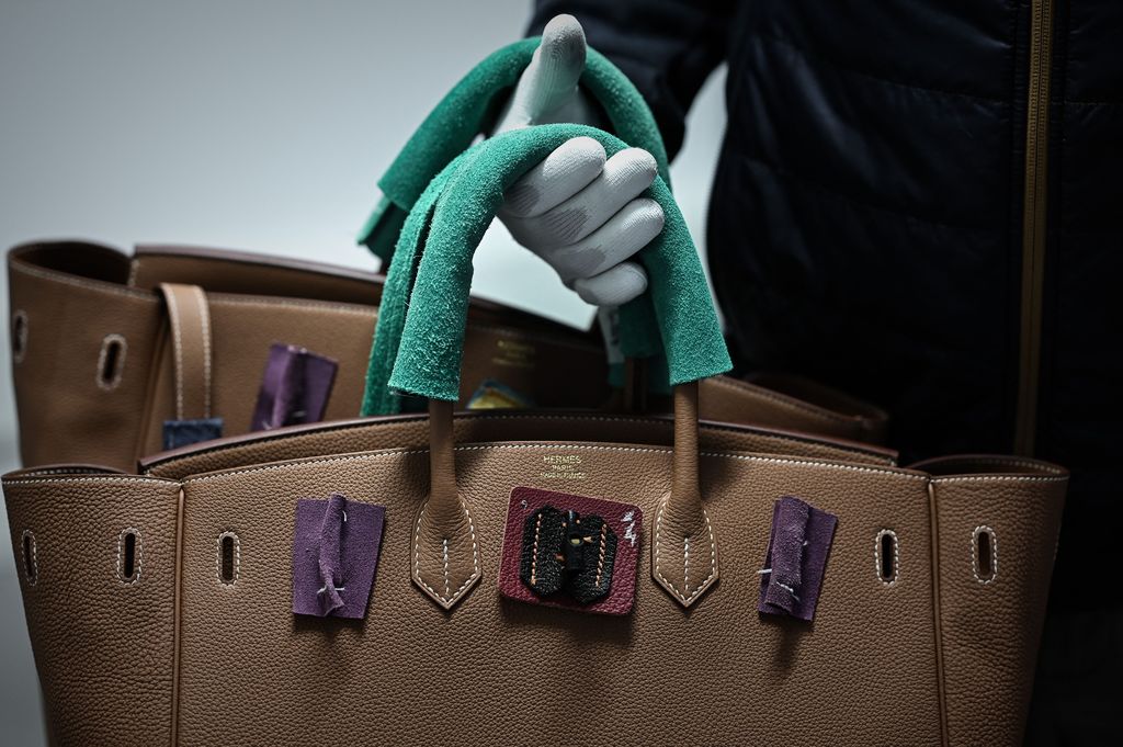 This picture taken on January 6, 2022 shows an employee holding handbags at the leather goods workshop of French high fashion luxury goods manufacturer Hermes in Montbron some 28 kms East of Angouleme. (Photo by Philippe LOPEZ / AFP) (Photo by PHILIPPE LOPEZ/AFP via Getty Images)