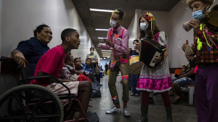 Atraksi Kelompok Badut di Brasil Hibur Pasien dengan Gelak Tawa Patient Angelo Saior, right, gestures as he watches the performance of the clown group of the Nonprofit Organization Doctors of Joy at the Adão Pereira Nunes hospital in Duque de Caxias, Brazil, Wednesday, June 29, 2022. The group that performs in different hospitals using laughter to help in the recovery of hospitalized patients and their families, resumed activities in recent months after two years away due to the COVID-19 pandemic. (AP Photo/Bruna Prado)