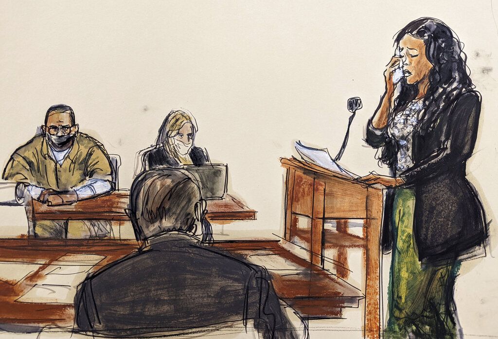 In this courtroom sketch, Kitti Jones, right, speaks during R. Kelly's sentencing in federal court, Wednesday, June 29, 2022, in New York. Kelly and his attorney Ashley Cohen are seated, background left. The former R&B superstar was convicted of racketeering and other crimes. (AP Photo/Elizabeth Williams)