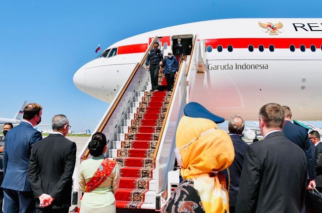 Tiba di Moskow, Iriana memadukan parka tersebut dengan hijab putih, celana panjang hitam dan sneakers senada. Gayanya selaras dengan Presiden Jokowi yang mengandalkan jaket bomber biru gelap beraksen putih pada bagian lengan, dan celana panjang serta sneakers serba hitam. (Foto: Anadolu Agency via Getty Images)