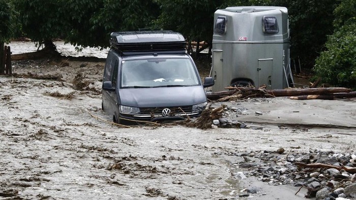 Hujan deras memicu banjir dan tanah longsor di tiga desa di Austria. Selain menerjang rumah, material longsor juga merendam sejumlah mobil. Ini penampakannya.