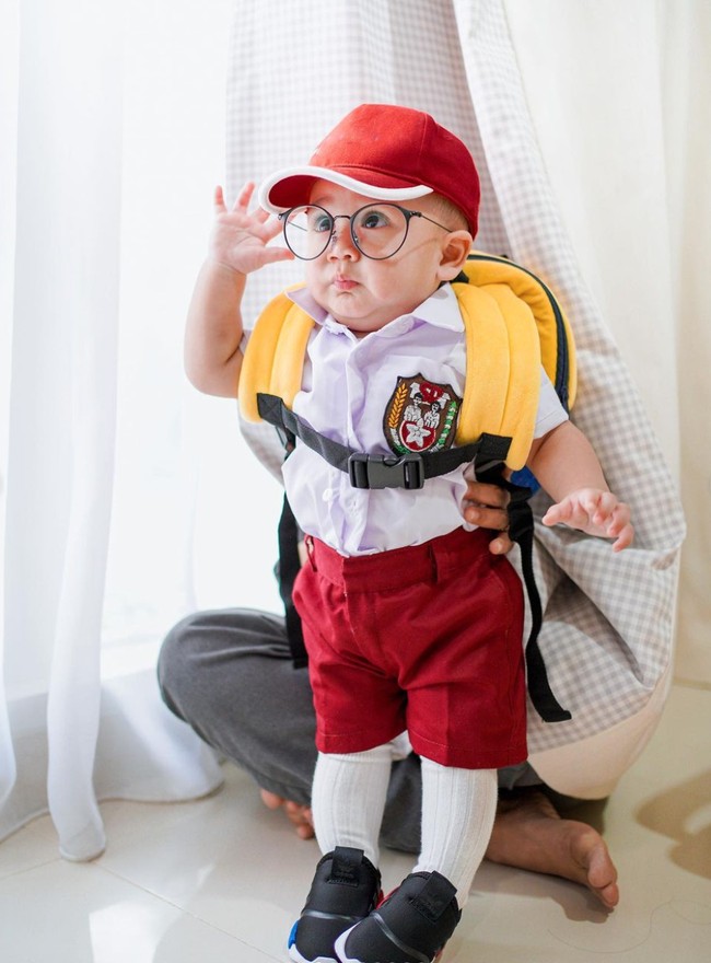 Seperti layaknya anak sekolahan, Rayyanza terlihat mengenakan seragam merah putih lengkap dengan tas ransel, topi, dan sepatu hitam. Kaos kaki putih yang dikenakannya pun terlihat begitu tinggi sampai menutupi hampir semua bagian kaki Rayyanza. Foto: Instagram/@raffinagita1717