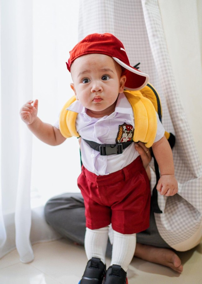 Bergaya seperti murid SD dengan topi yang dimiringkan seperti ini, penampilan Rayyanza berhasil curi atensi dan membuat netizen menjadi gemas. Ditambah dengan ekspresi wajah seperti di dalam foto, Rayyanza benar-benar bikin pengin cubit. Foto: Instagram/@raffinagita1717