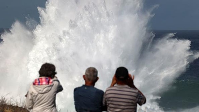 Residents watch the waves during a breaking swell in Saint-Leu, in the south of the French island of Reunion, Indian Ocean, on June 29, 2022, after a wave-submergence alert was declared. (Photo by Richard BOUHET / AFP) (Photo by RICHARD BOUHET/AFP via Getty Images)