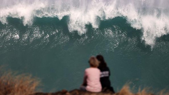Saat Ombak Besar di Samudra Hindia Jadi Tontonan Warga Prancis Residents watch the waves during a breaking swell in Saint-Leu, in the south of the French island of Reunion, Indian Ocean, on June 29, 2022, after a wave-submergence alert was declared. (Photo by Richard BOUHET / AFP) (Photo by RICHARD BOUHET/AFP via Getty Images)