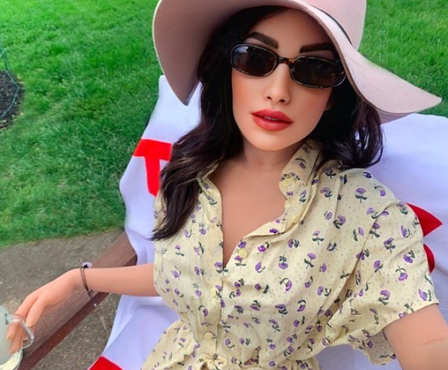 Ini salah satu posenya. Sang boneka seks tampak mengenakan kemeja floral dengan topi dan kacamata.Foto: dok. Instagram/@ tasha_marie_86