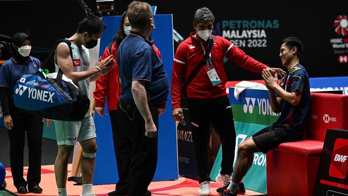 Cedera, Vito Keluar Axiata Arena dengan Kursi Roda Japan's Kento Momota (2nd L) gestures as he leaves the court after his opponent Indonesia's Rhustavito Shesar Hiren (R) retired due an injury during their mens singles quarter-final match at the Malaysia Open badminton tournament in Kuala Lumpur on July 1, 2022. (Photo by Mohd RASFAN / AFP) (Photo by MOHD RASFAN/AFP via Getty Images)