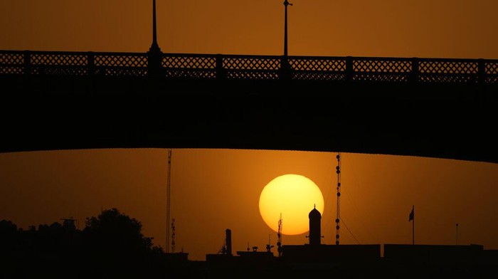 The sun sets behind Al-Ahrar bridge over the Tigris Rive in Baghdad, Iraq, Tuesday, June 28, 2022. (AP Photo/Hadi Mizban)