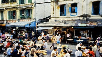 Foto mengenai masa silam selalu menimbulkan daya tarik layaknya mesin waktu. Ini suasana Sigapura pada tahun 1980-an. Tampak ramai orang makan di pinggir jalan, di depan bangunan yang usang. Foto: Vintag.es