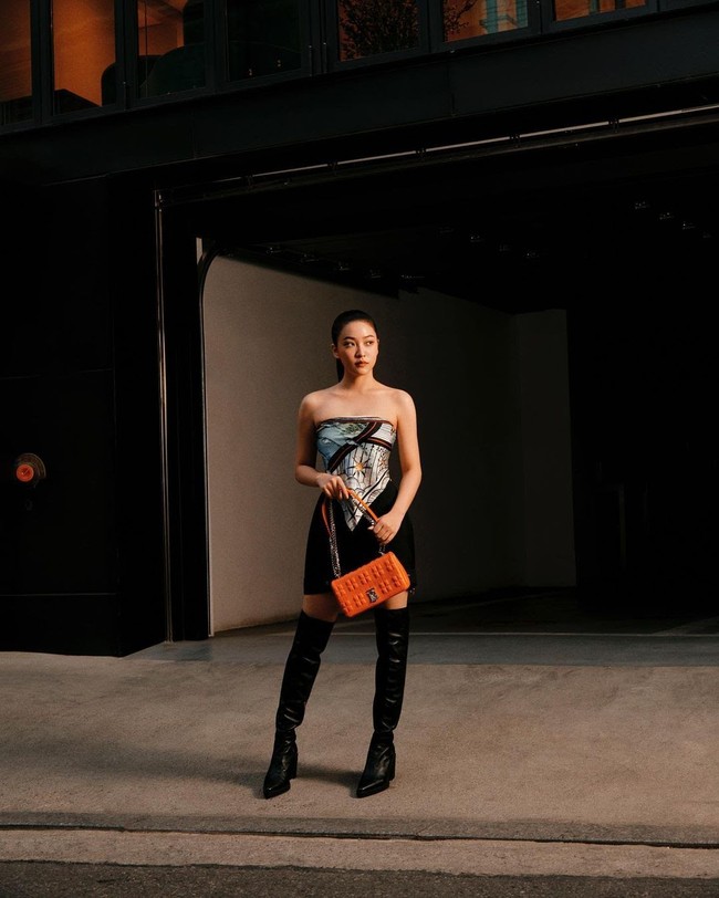 Gaya Yeri Red Velvet bisa menjadi inspirasi untuk cewek mamba yang ingin menambahkan warna lain selain hitam. Dia memakai scarf bernuansa hitam dan oranye yang dipadukan dengan koleksi tas Burberry ‘The Lola Bag’ berwarna pop oranye. Penampilannya semakin chic dengan gaya rambut sleek dan overknee boots hitam. Foto: dok. Burberry