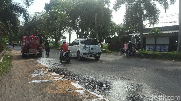 Petugas Damkar membersihkan tumpahan oli di Jalan Raya Demak Kudus, Desa Mranak, Demak, Sabtu (2/7/2022).