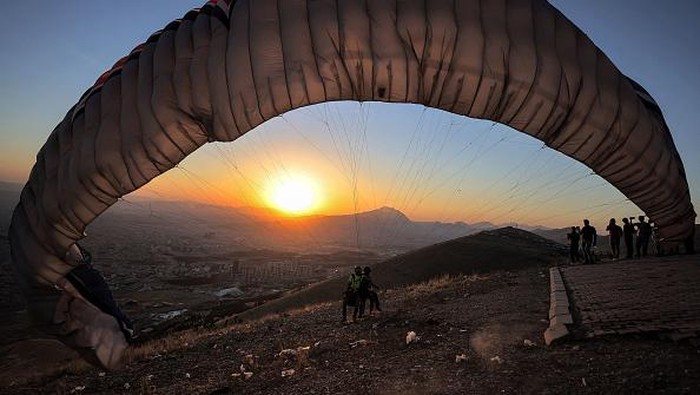 Sensasi Terbang di Atas Keindahan Kota Sulaymaniyah, Irak Members of the Sulaymaniyah paragliding team glide after a sunset launch from Mount Azmar over Iraq's northeastern city of Sulaymaniyah in the autonomous Kurdistan region on July 1, 2022. (Photo by AHMAD AL-RUBAYE / AFP) (Photo by AHMAD AL-RUBAYE/AFP via Getty Images)