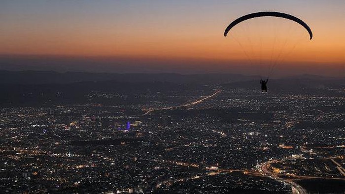 Members of the Sulaymaniyah paragliding team glide after a sunset launch from Mount Azmar over Iraq's northeastern city of Sulaymaniyah in the autonomous Kurdistan region on July 1, 2022. (Photo by AHMAD AL-RUBAYE / AFP) (Photo by AHMAD AL-RUBAYE/AFP via Getty Images)