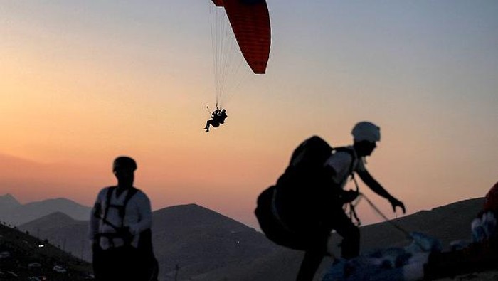 Members of the Sulaymaniyah paragliding team glide after a sunset launch from Mount Azmar over Iraqs northeastern city of Sulaymaniyah in the autonomous Kurdistan region on July 1, 2022. (Photo by AHMAD AL-RUBAYE / AFP) (Photo by AHMAD AL-RUBAYE/AFP via Getty Images)