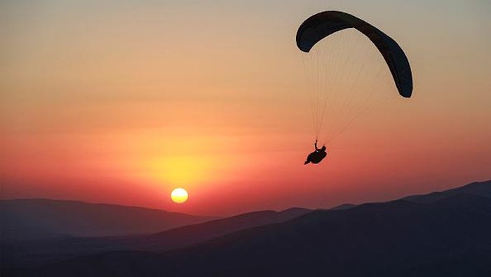 Members of the Sulaymaniyah paragliding team glide after a sunset launch from Mount Azmar over Iraqs northeastern city of Sulaymaniyah in the autonomous Kurdistan region on July 1, 2022. (Photo by AHMAD AL-RUBAYE / AFP) (Photo by AHMAD AL-RUBAYE/AFP via Getty Images)